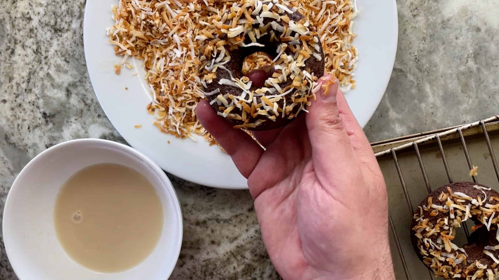 doughnut assembly into glaze and toasted coconut