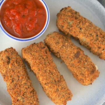4 mozzarella sticks on a plate with red dipping sauce