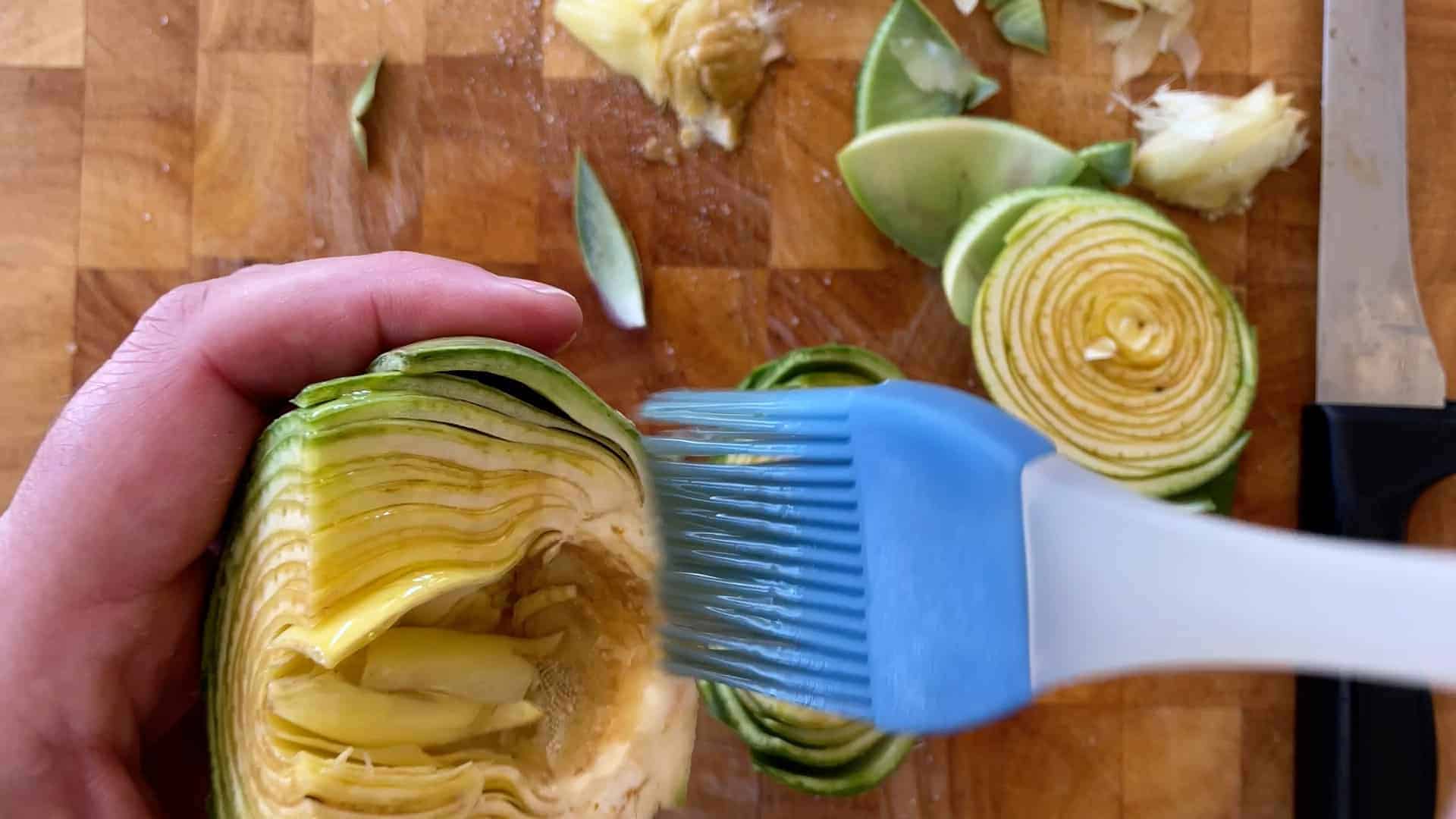 Brushing artichokes with olive oil