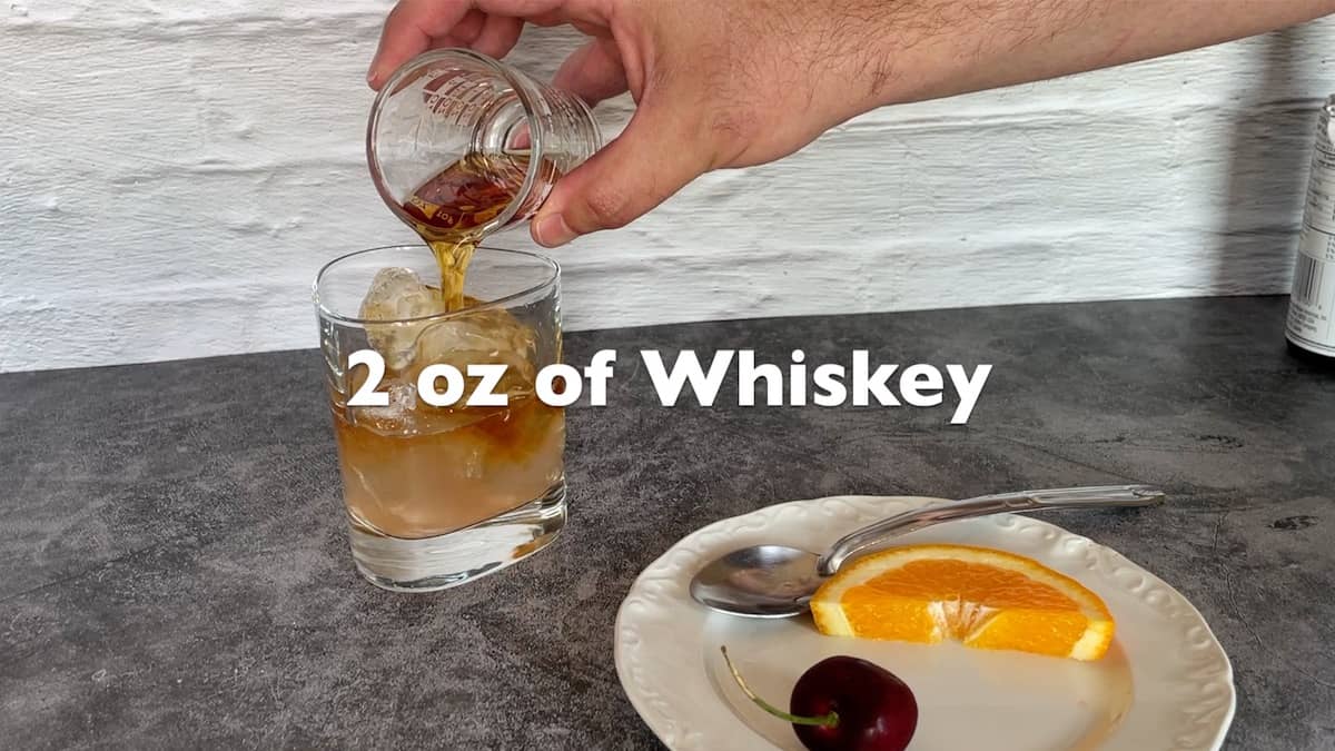 adding the whiskey to the glass