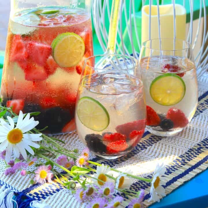 a pitcher of sangria with two glasses outdoors with flowers