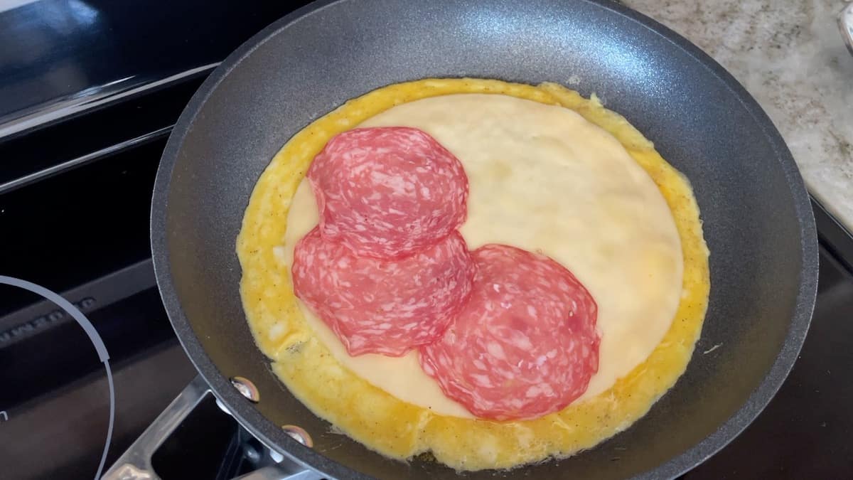 adding salami to omelet