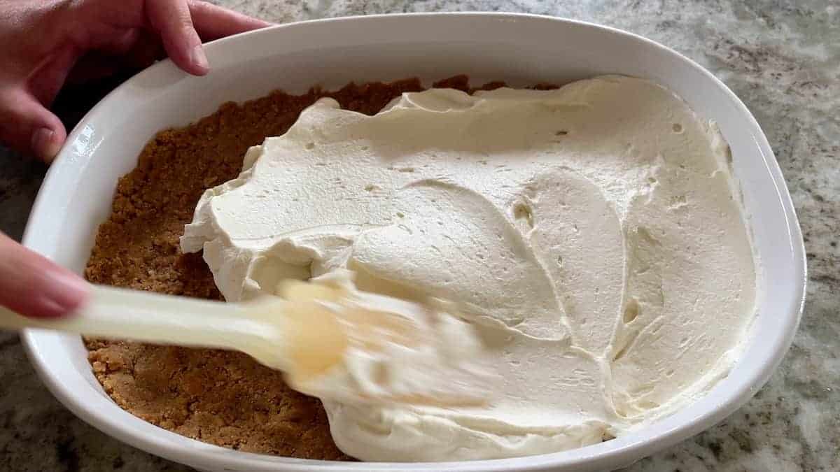 spreading cream cheese mixture over the crumbs