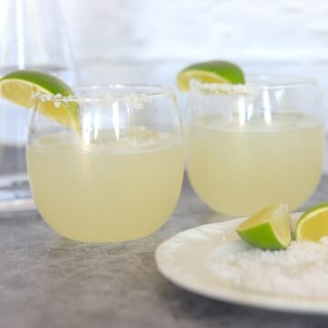 two glasses of margarita with lime wedges