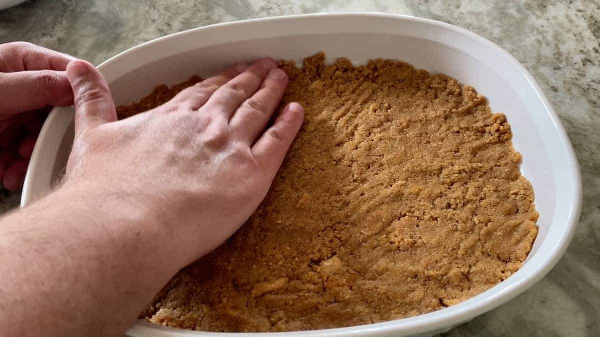 firmly pressing the crumbs into the cheesecake dish