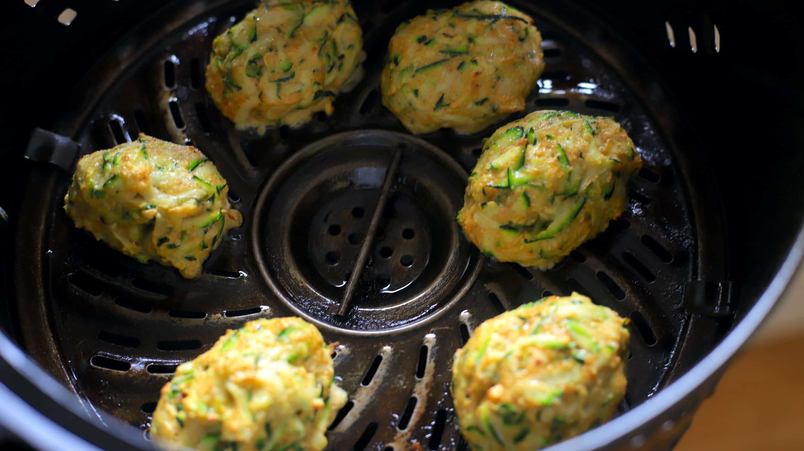 6 raw zucchini fritters in air fryer basket