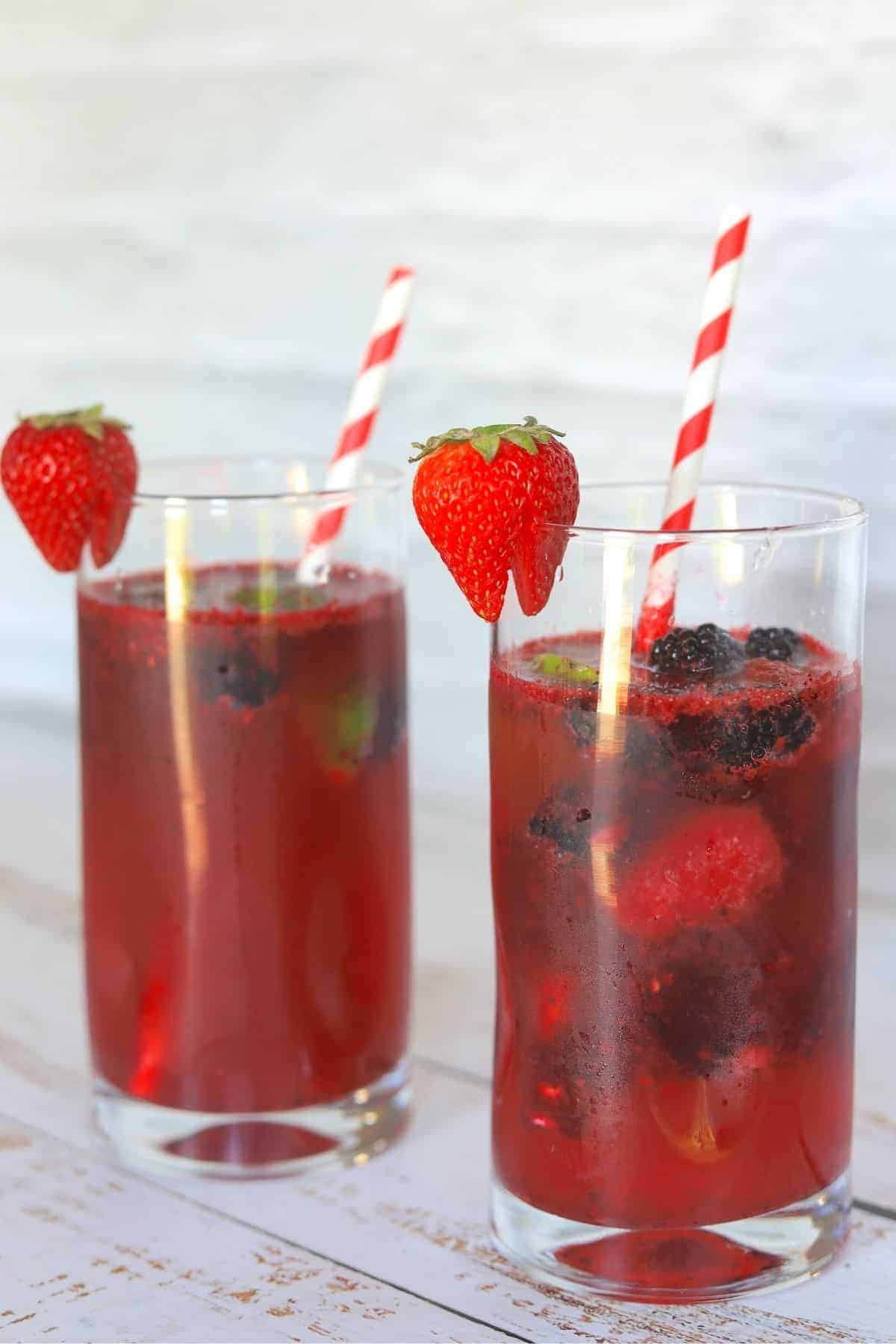 2 tall glasses filled with berry daiquiris a straw and garnished with a strawberry