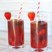2 tall glasses filled with berry daiquiris a straw and garnished with a strawberry