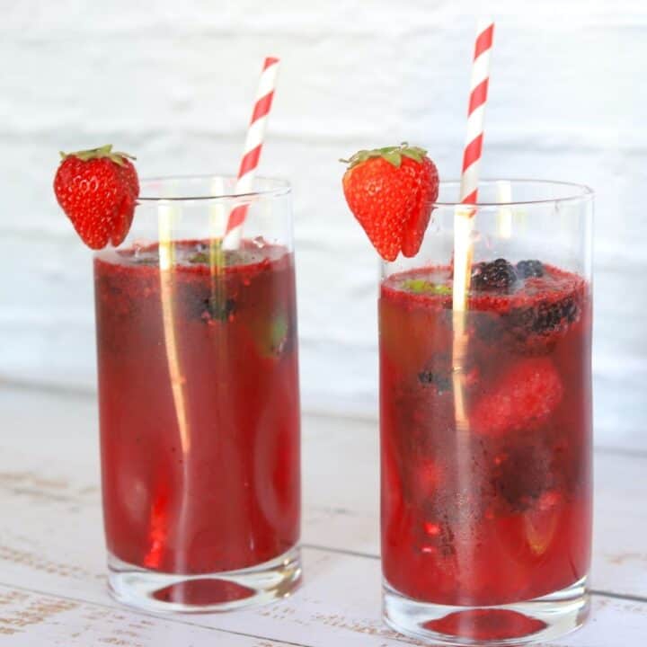 2 tall glasses filled with berry daiquiris a straw and garnished with a strawberry