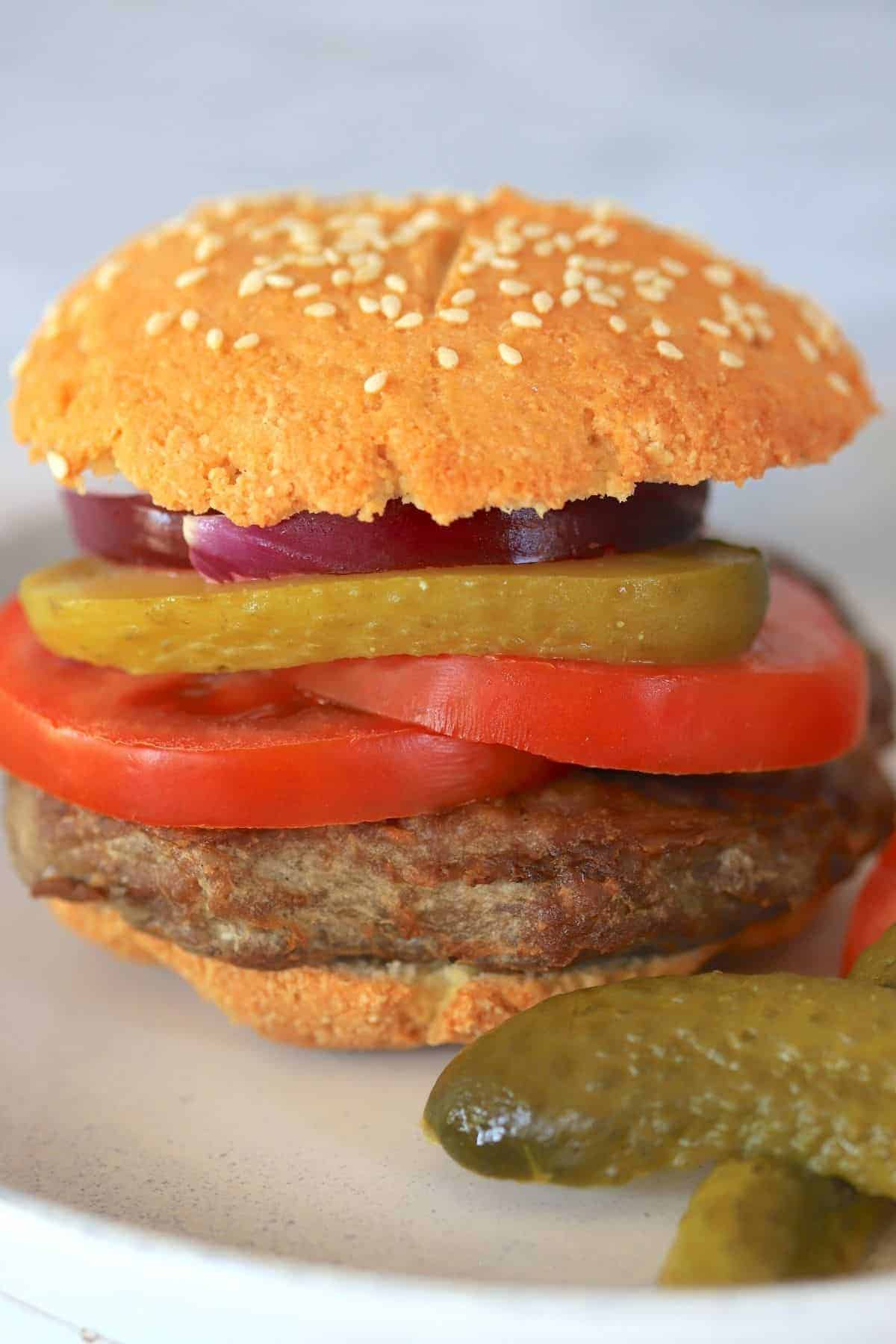 hamburger with bun on a plate with tomatoes onion and pickles