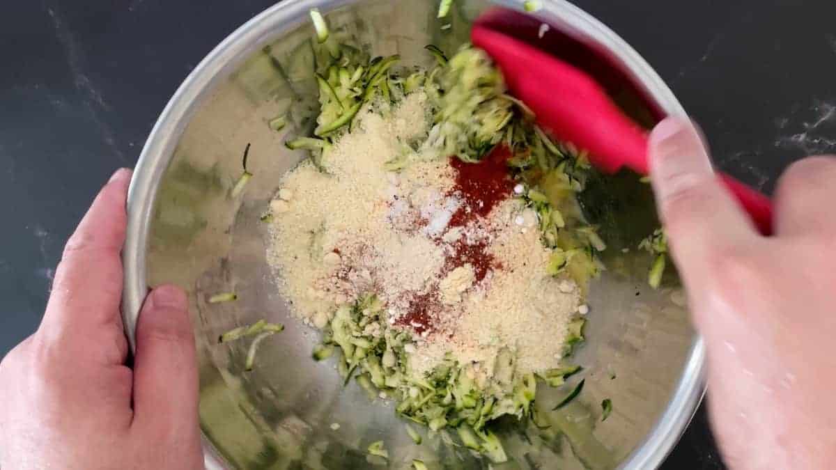 Mixing the shredded zucchini with almond flour and spices