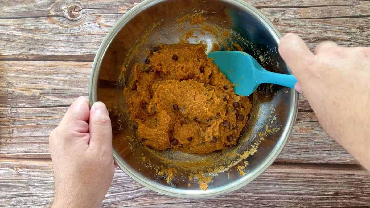 mixing the batter with a blue spatula in a large bowl