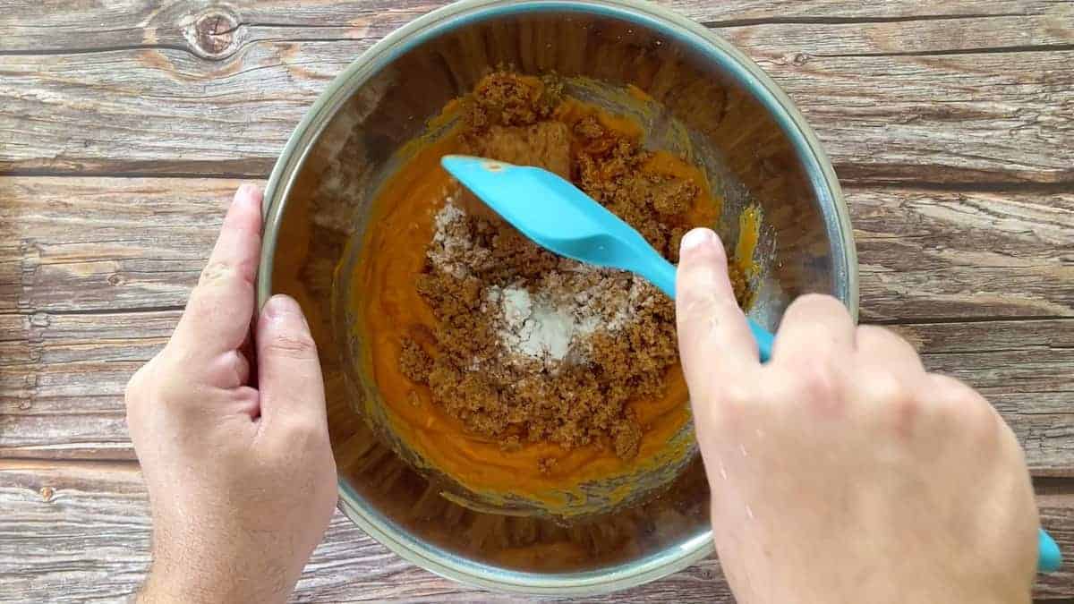 mixing the batter with a blue spatula in a large bowl