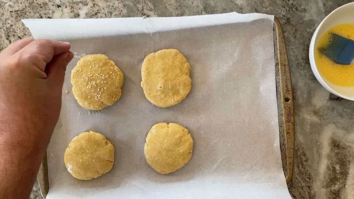 4 hamburger buns on a parchment lined baking sheet