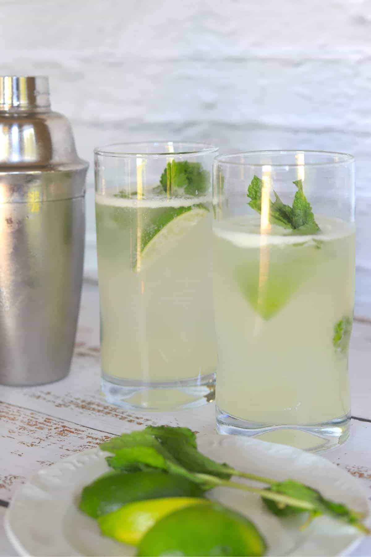2 glasses filled with mojito lime wedge and sprig of mint