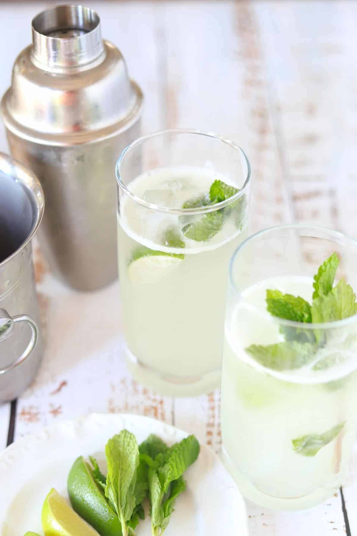 2 glasses filled with mojito lime wedge and sprig of mint