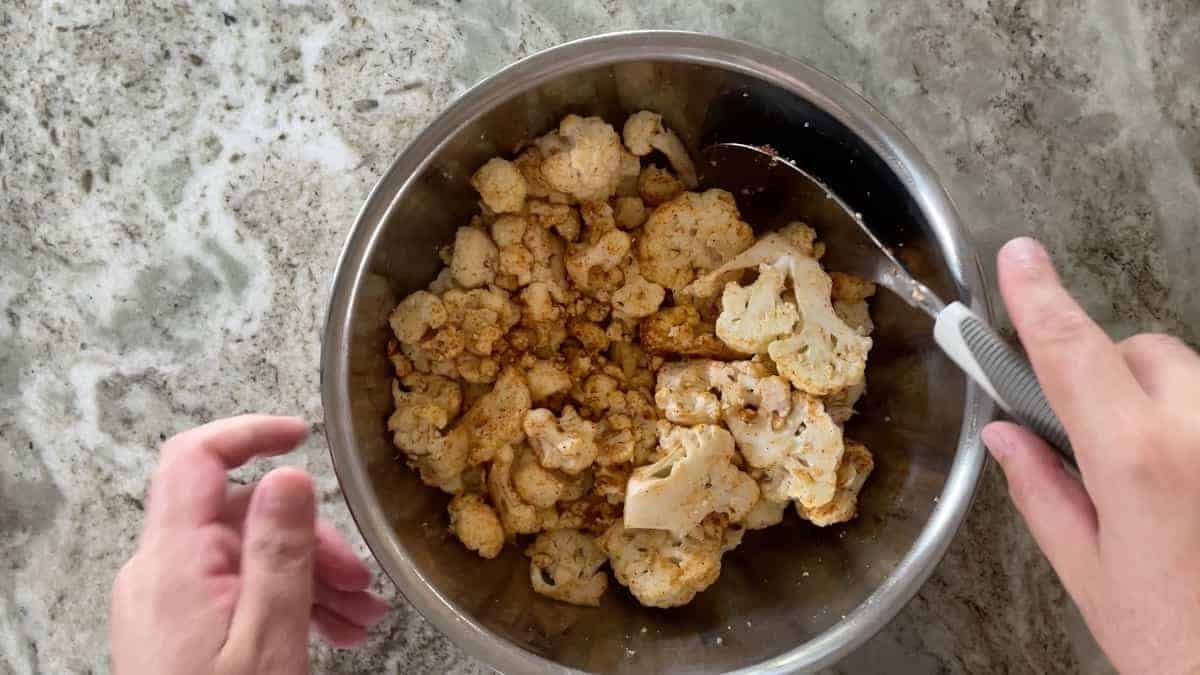 tossing the cauliflower in a large bowl