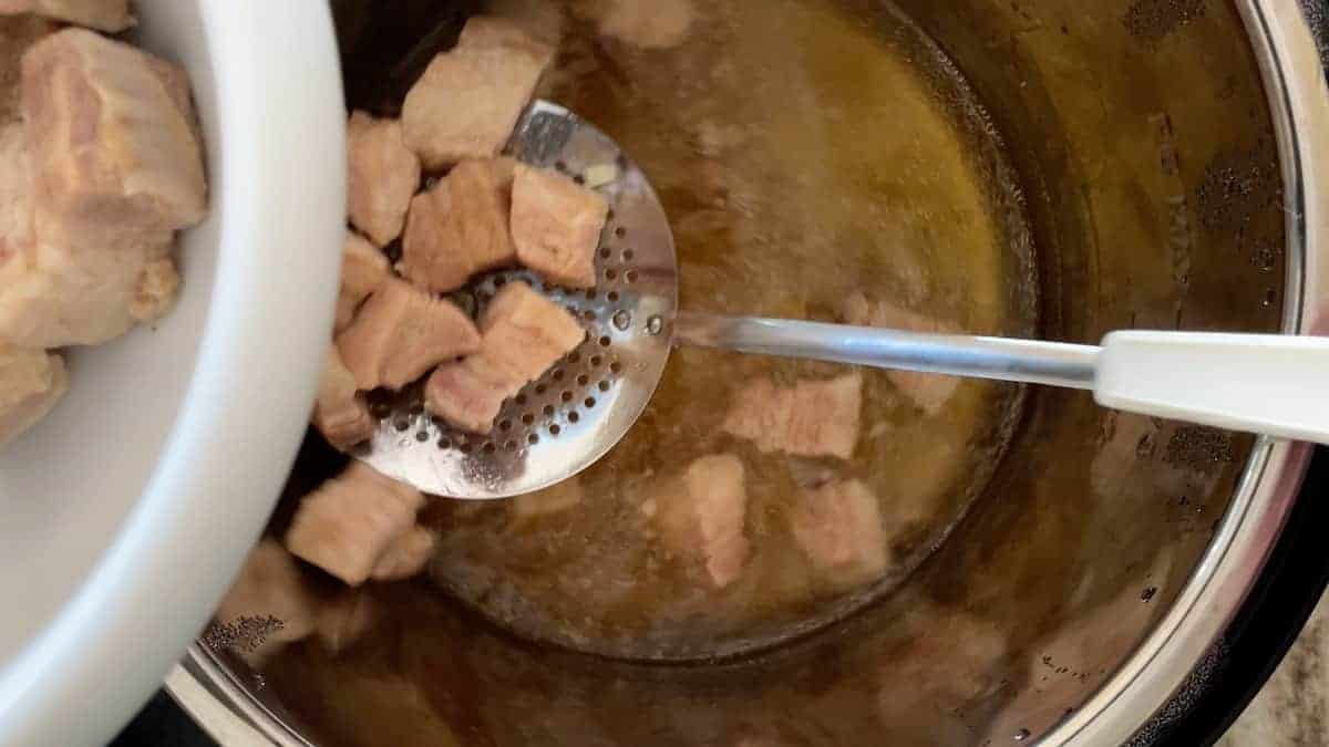 pork belly in the instant pot with a slotted spoon