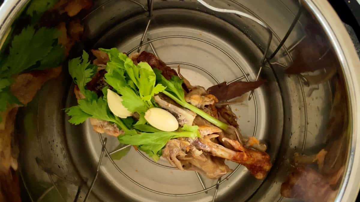chicken carcass in instant pot with celery leaves and garlic