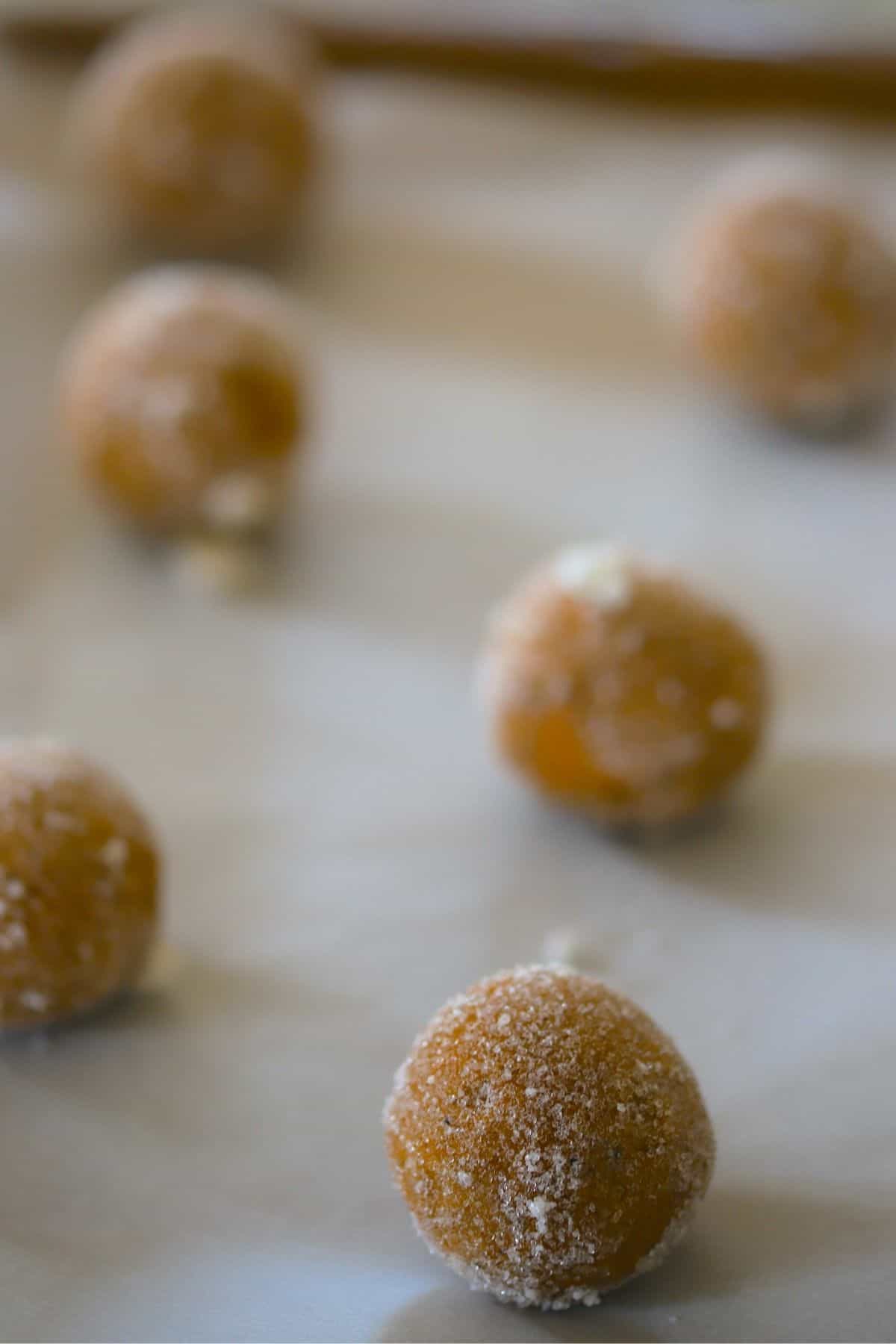 cookie dough balls on a parchment lined cookie sheet