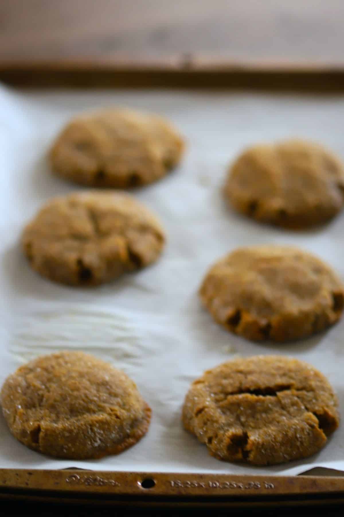 six pumpkin spice cookies on a parchment lined cookie sheet