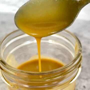 Spoon with caramel dripping into a glass jar