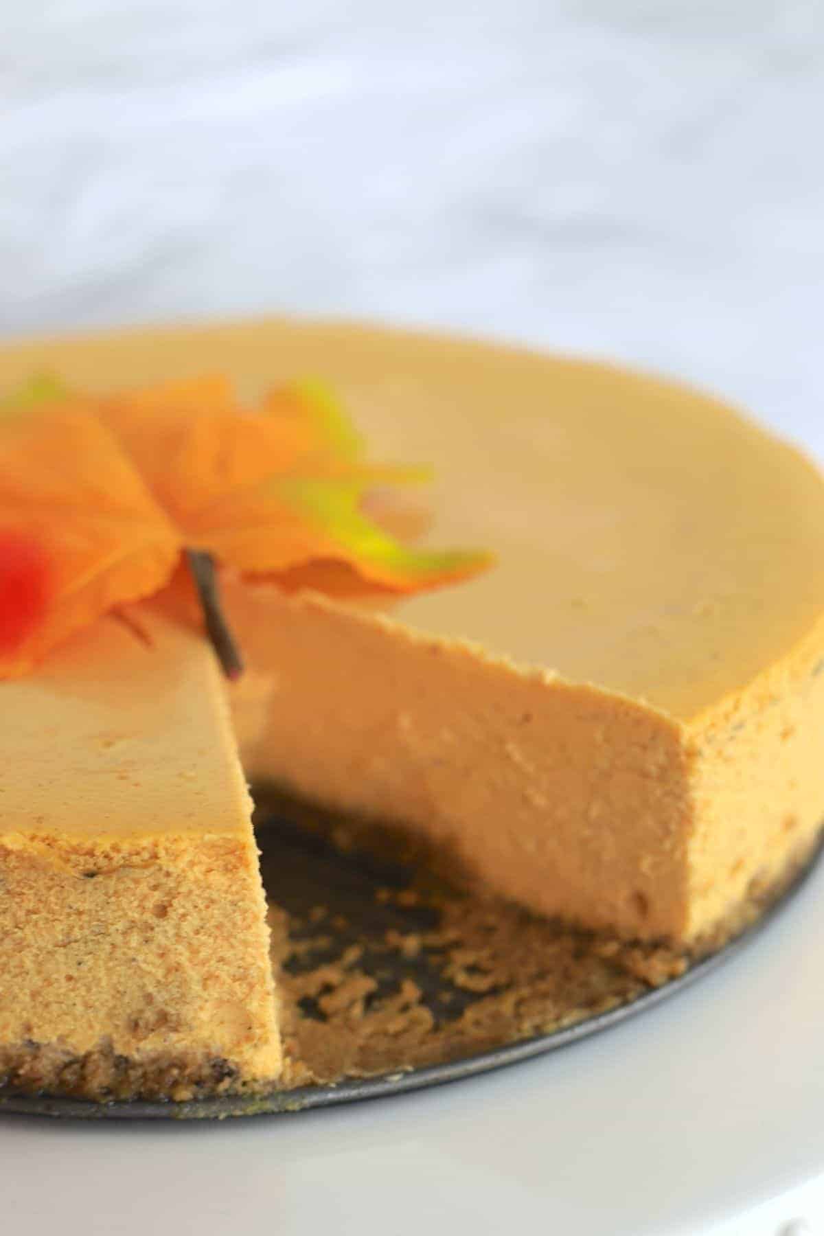 pumpkin cheesecake on a platter with a slice missing