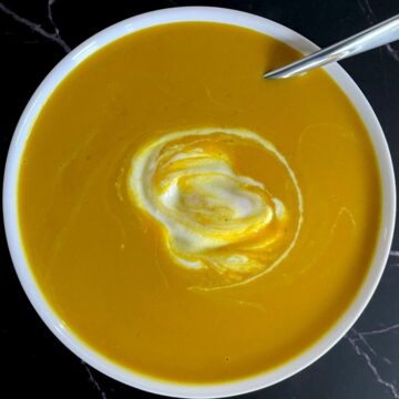 white bowl with soup, spoon and dollop of sour cream