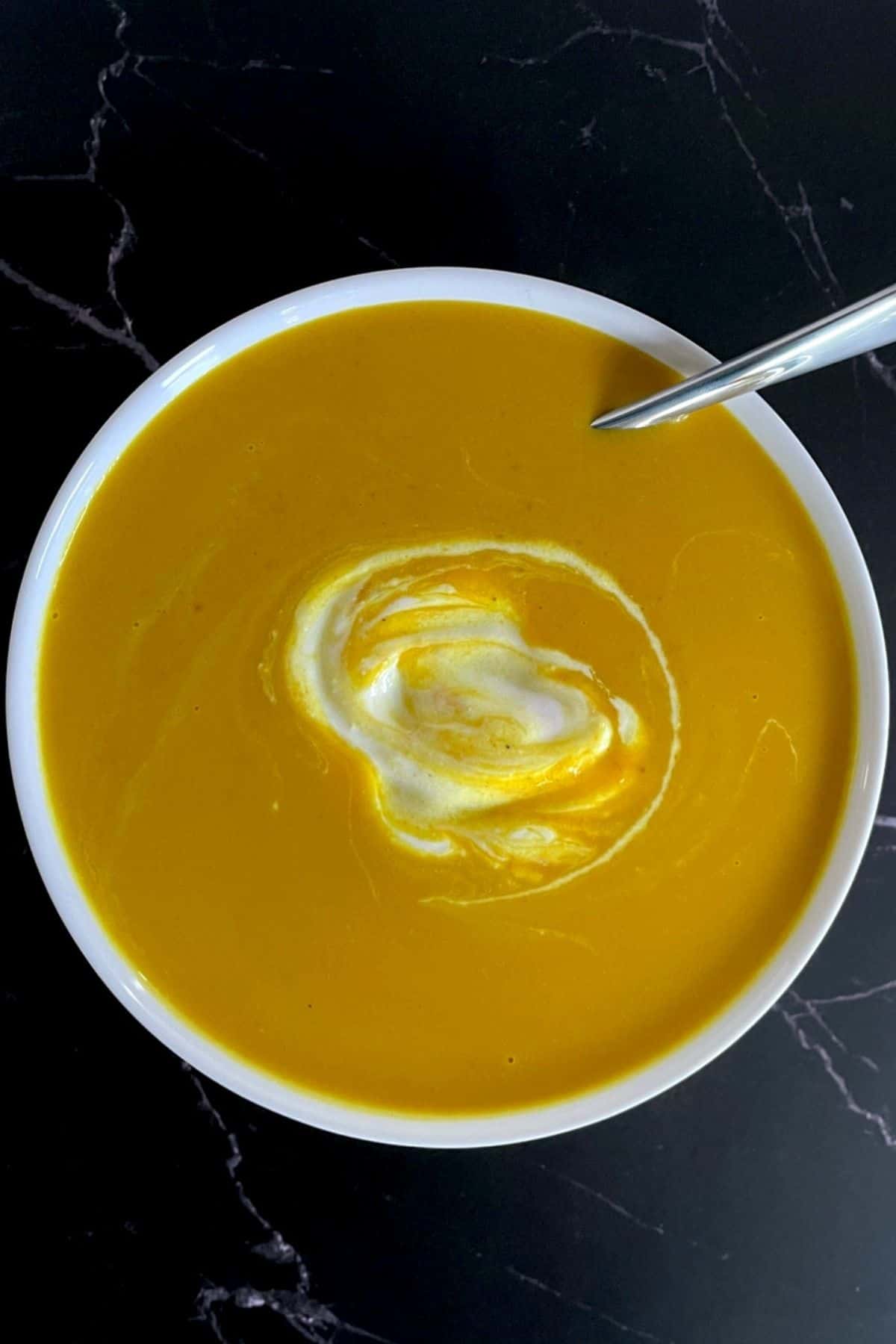 white bowl with soup, spoon and dollop of sour cream