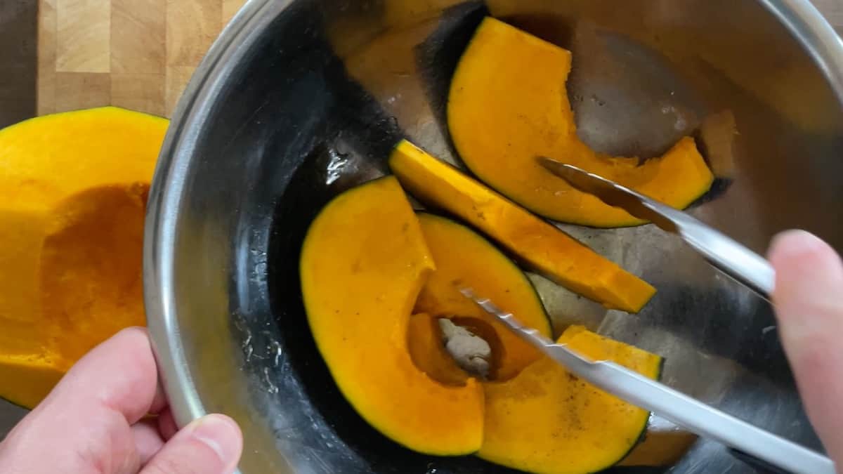 kabocha squash wedges in a bowl with tongs