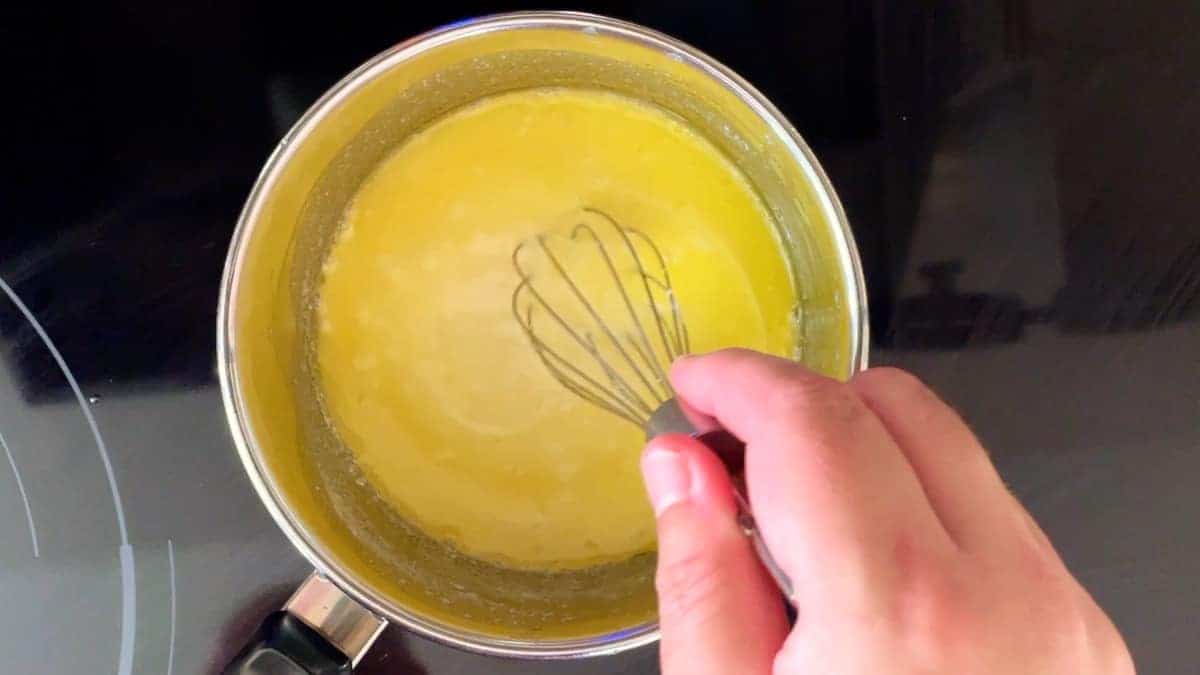 stirring sauce in a pot with a whisk