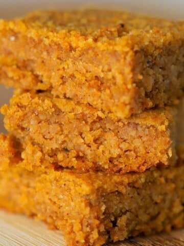 3 Keto Pumpkin Spice Blondies stacked on top of each other on a cutting board