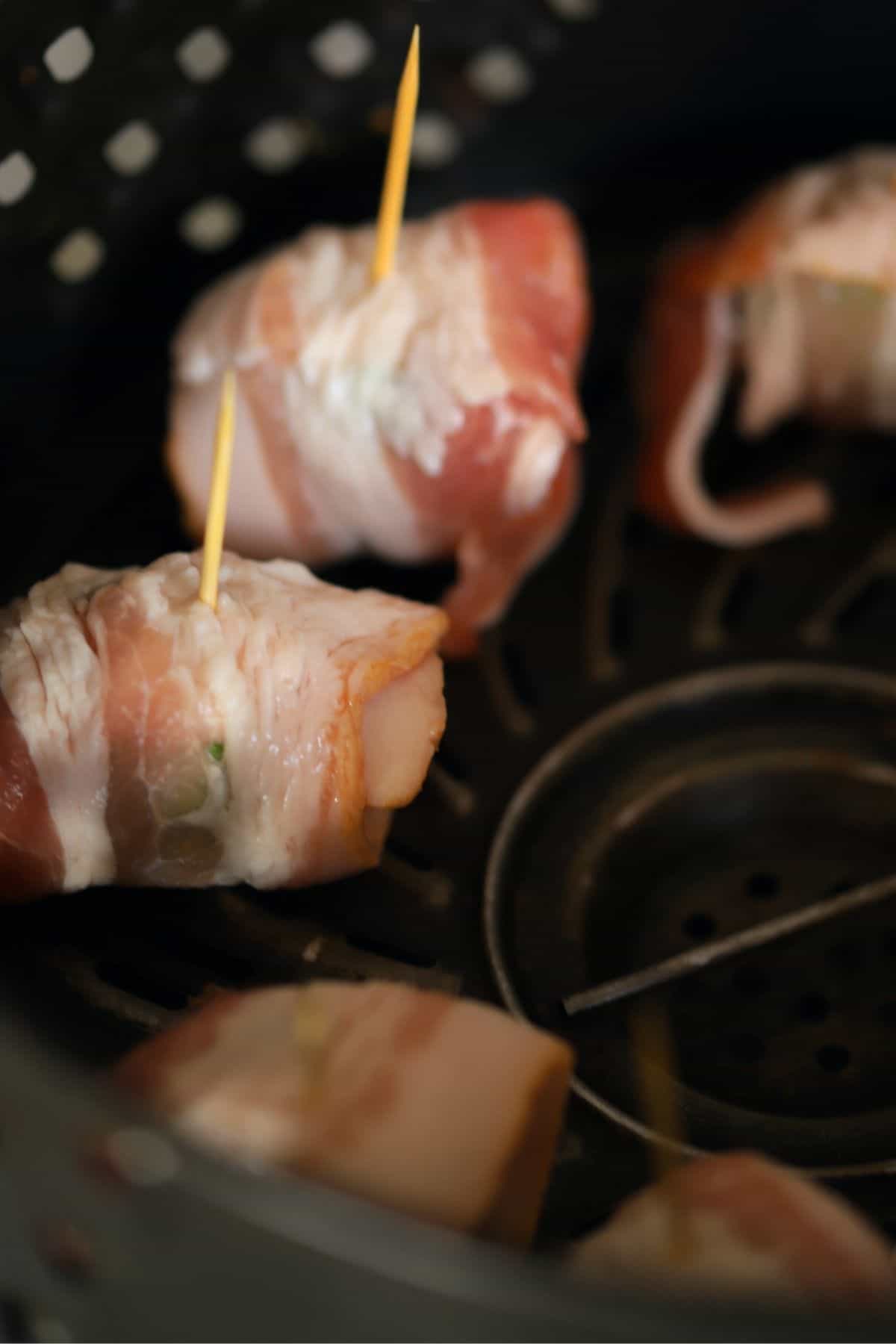 uncooked bacon wrapped brussel sprouts in the air fryer basket