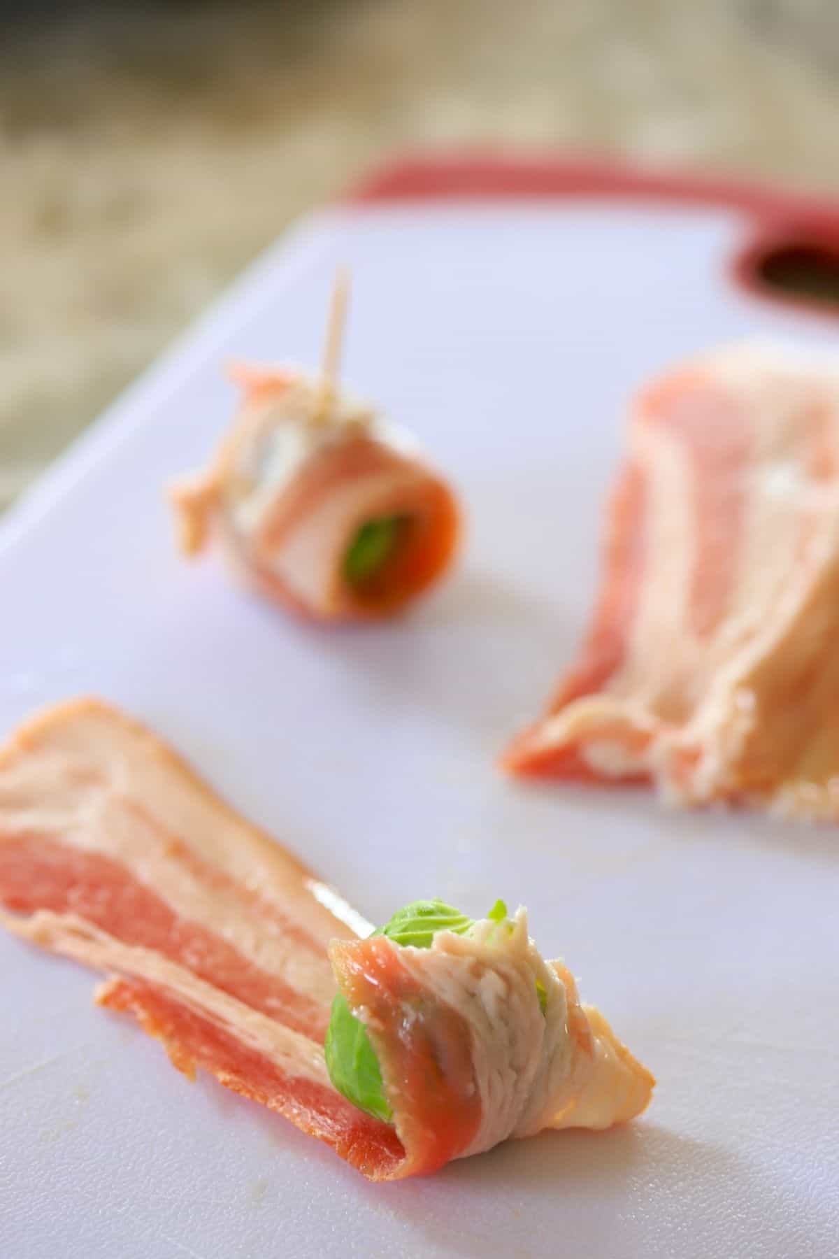 wrapping brussel sprouts with bacon on a cutting board