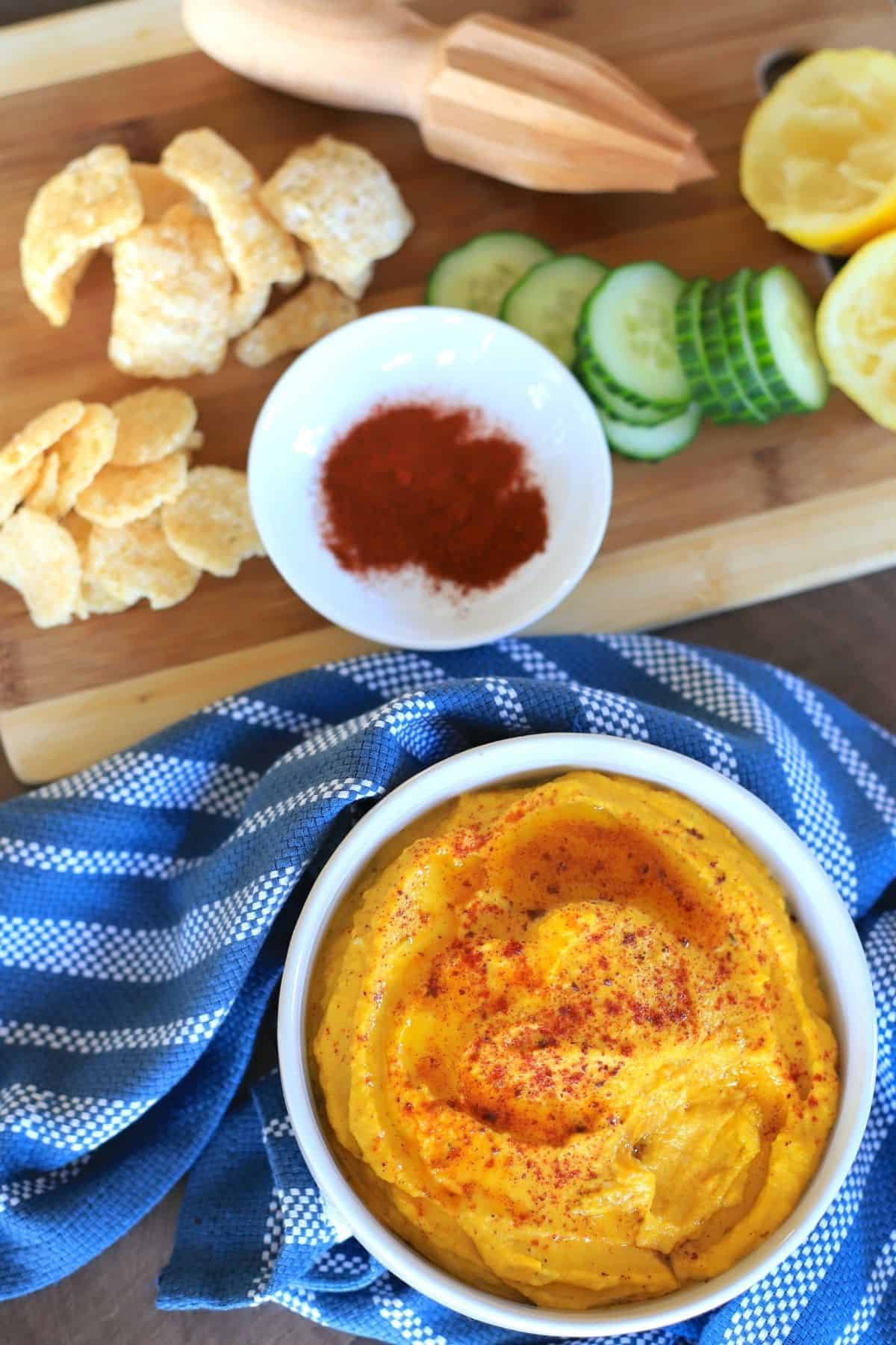 bowl of kabocha hummus with pork rinds, whisps, cucumbers and lemon