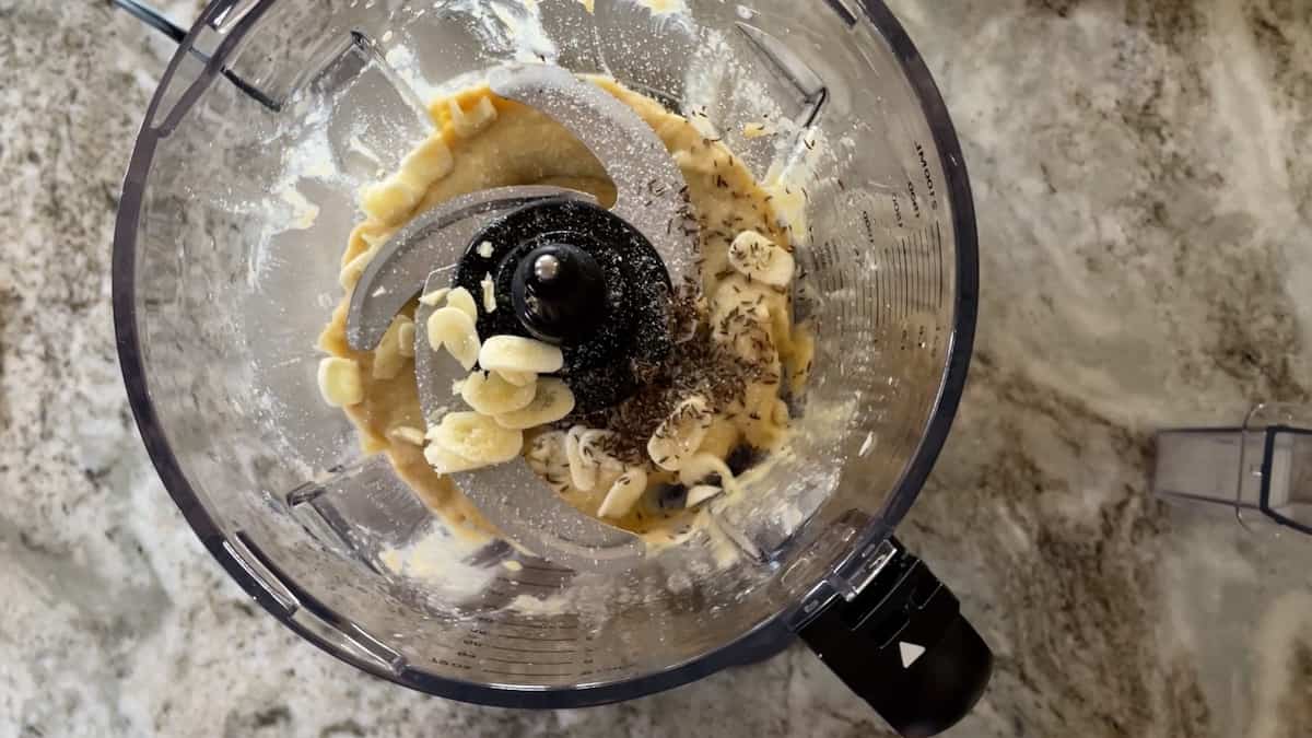 food processor with tahini and garlic slices