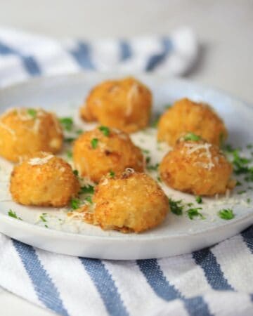 cauliflower balls on a plate garnished with parsley and parmesan