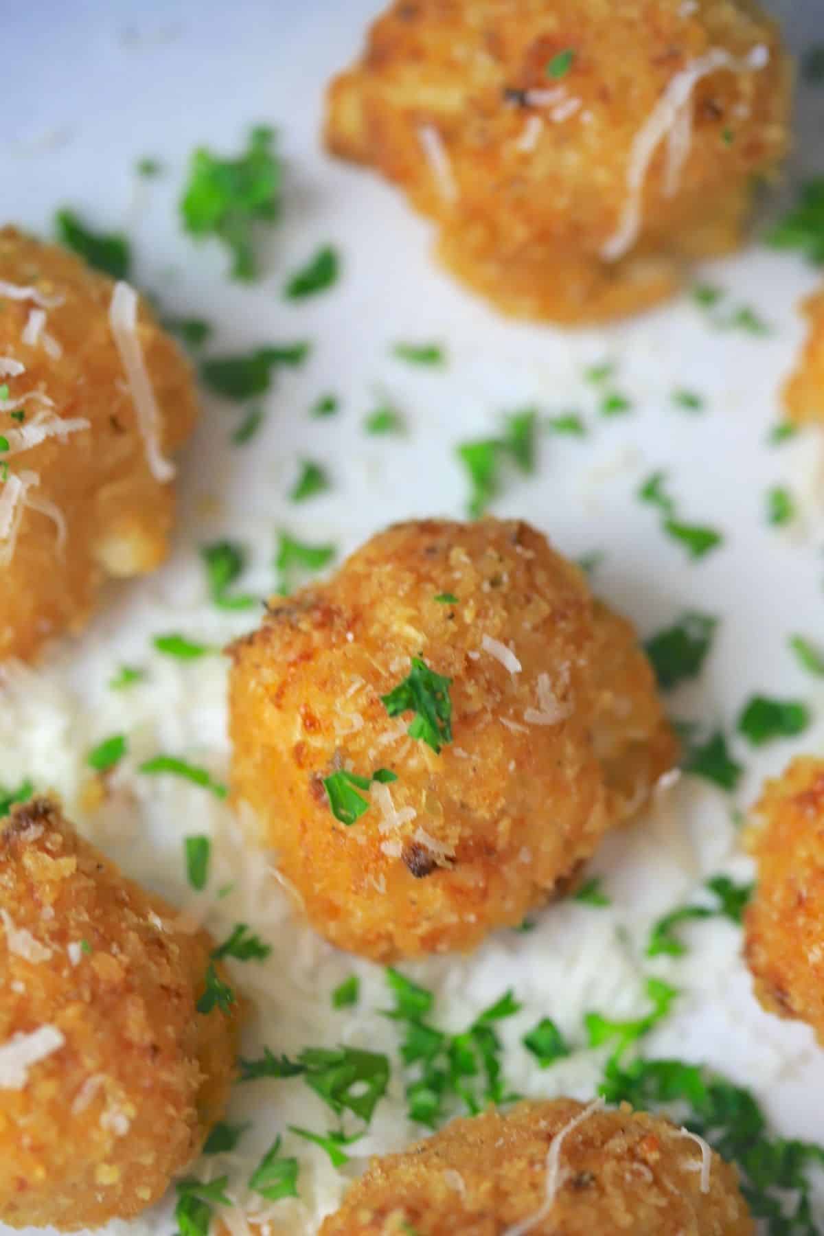 cauliflower balls on a plate garnished with parsley and parmesan