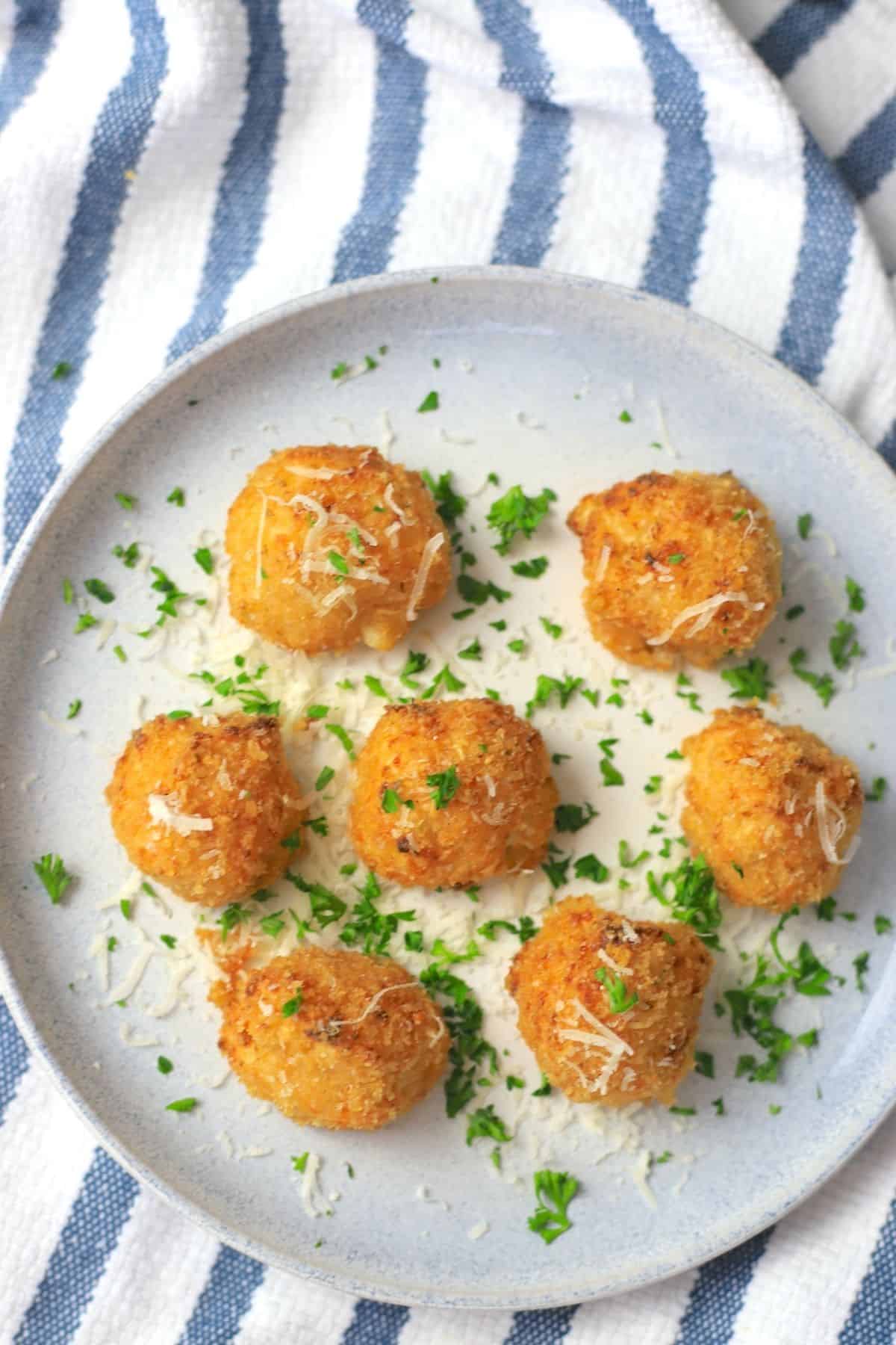 cauliflower balls on a plate garnished with parsley and parmesan