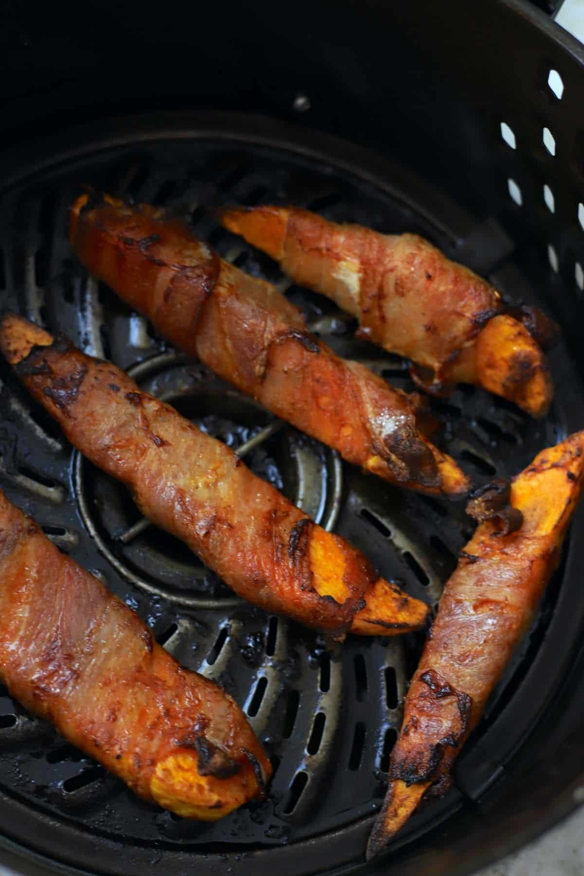 5 bacon wrapped sweet potatoe wedges in air fryer basket