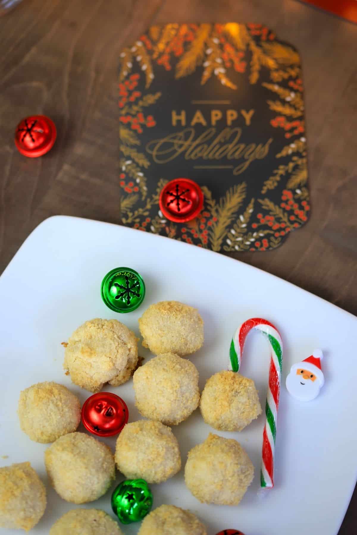 keto crunch shortbread cookies on a white plate with candy cane and bells and a holiday card
