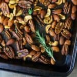 mixed nuts with rosemary on a baking sheet