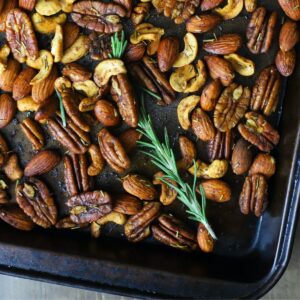 mixed nuts with rosemary on a baking sheet