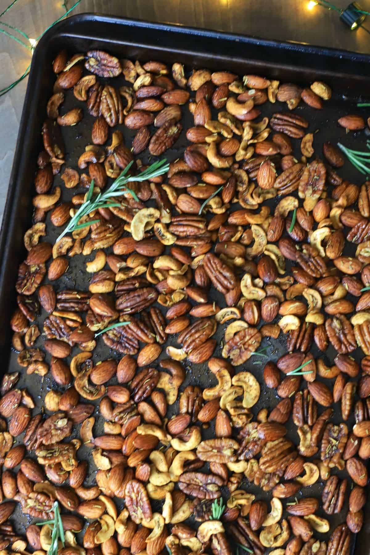 mixed nuts with rosemary on a baking sheet