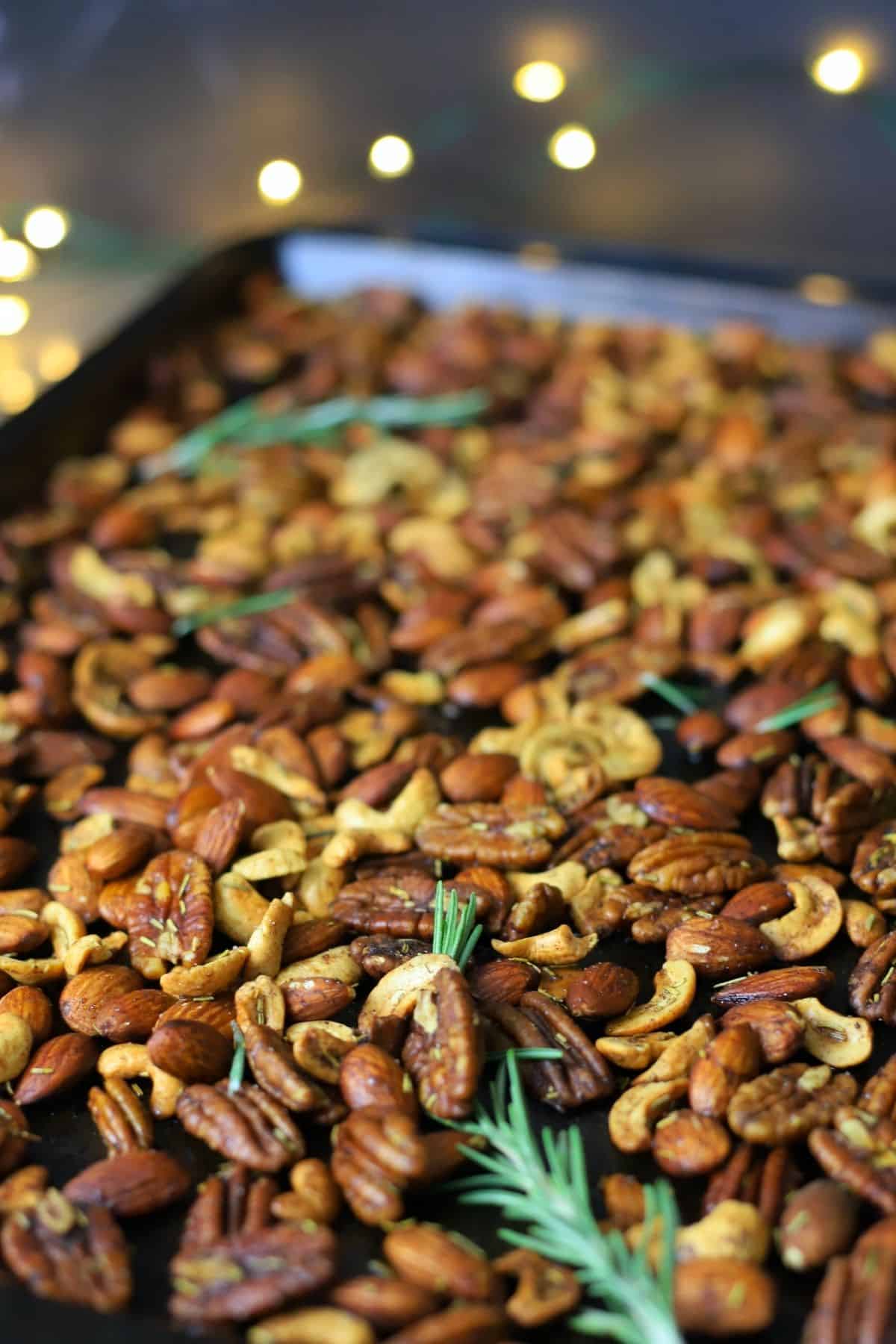 mixed nuts with rosemary on a baking sheet