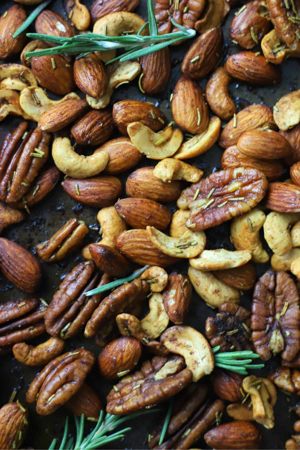 mixed nuts with rosemary on a baking sheet