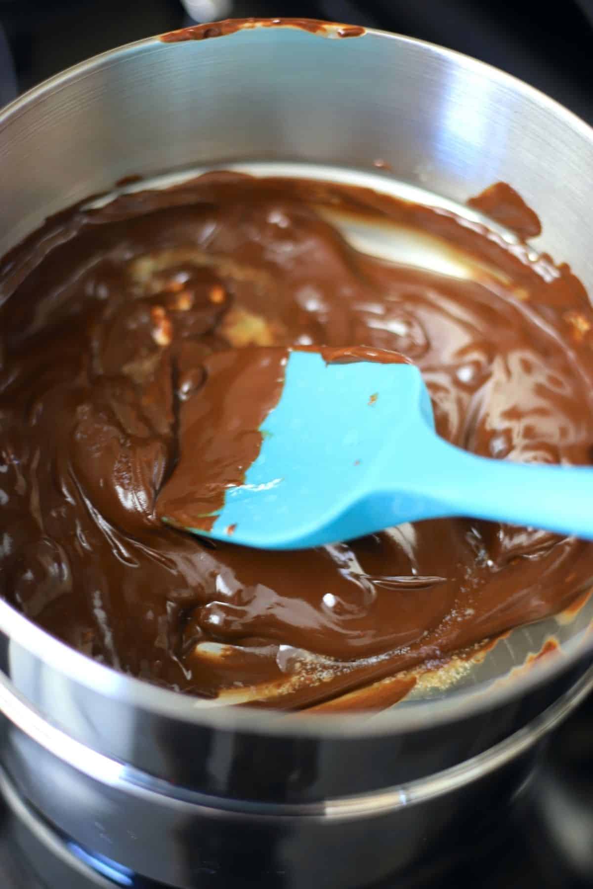 chocolate melting in a double boiler with a blue spatula.