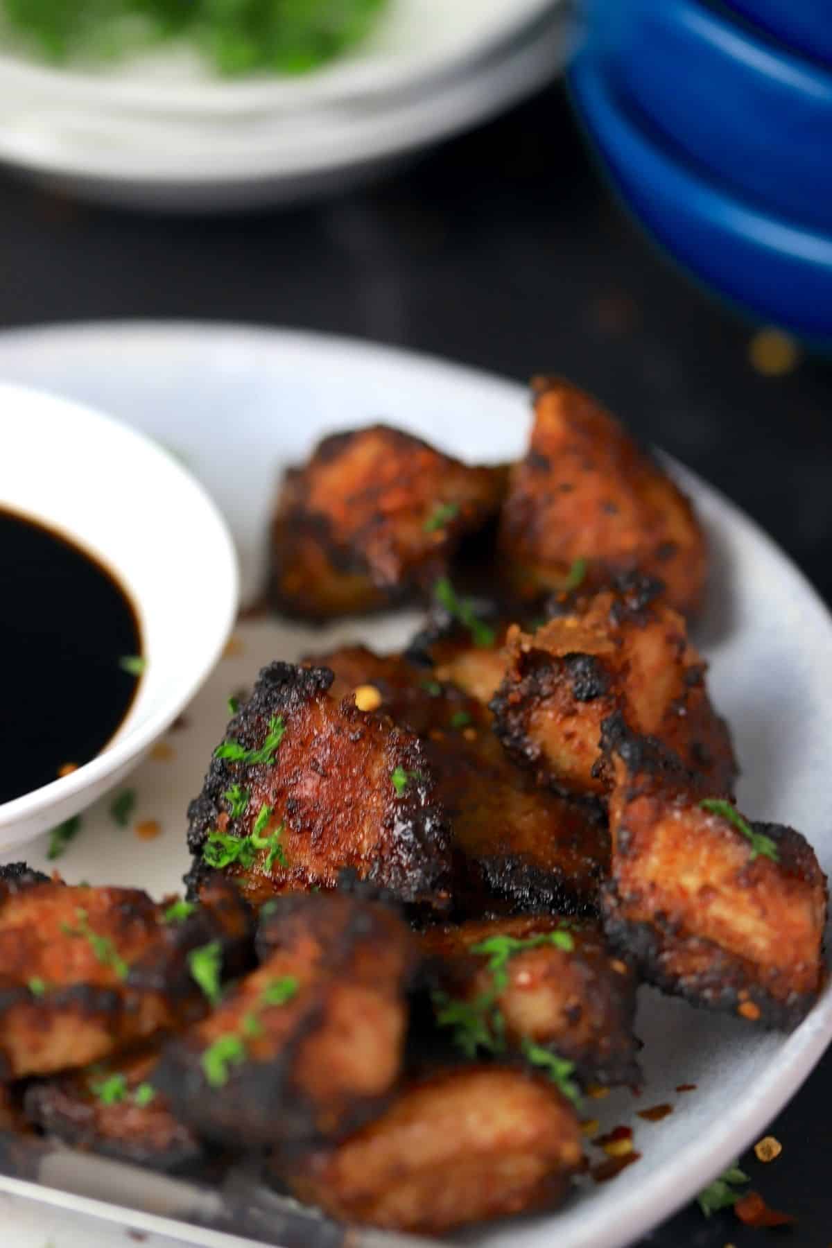 keto air fryer pork belly on a white plate with a fork and a bowl of soy sauce