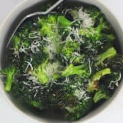 bowl of broccoli sprinkled with parmesan and a fork.