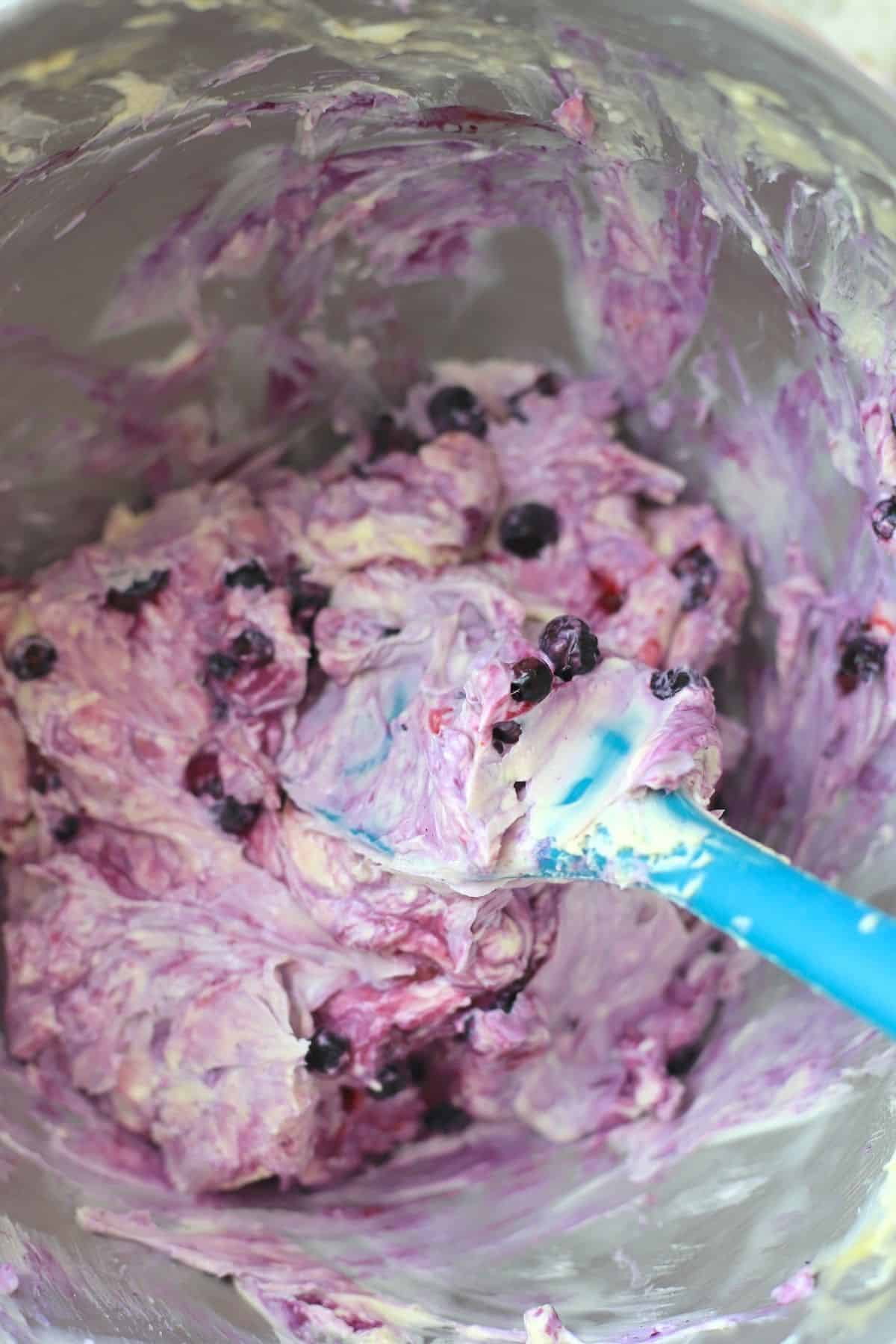 cheesecake batter in a bowl with a blue rubber spatula